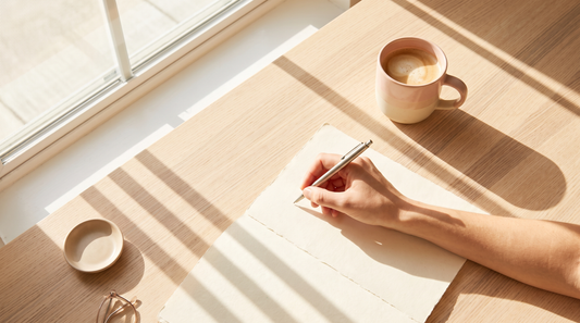 Hand writing on paper in morning light, unlock emotional clarity with 90 days of journaling
