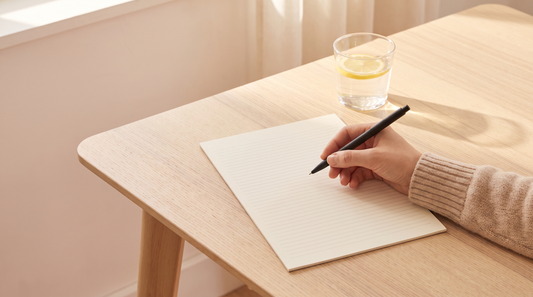 Hand with a pen hovering over a blank sheet of paper in bright morning light, journaling prompts for secret love and why structure wins