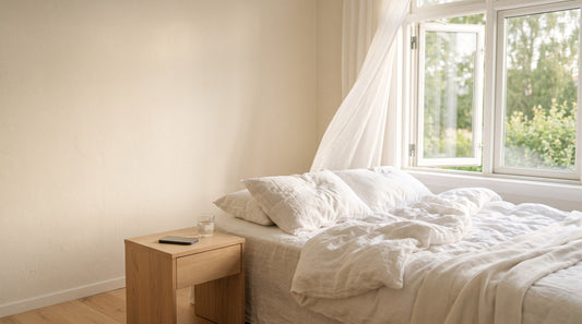 Sonniges Schlafzimmer im Sommer, offenes Fenster, Handy mit dem Display nach unten auf dem Nachttisch
