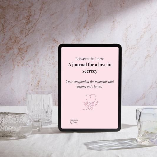 Cover of the love in secrecy journal standard edition in pink with the title between the lines: a journal for a love in secrecy - your companion for moments that belong only to you including a heart illustration on table with an empty bottle and two glasses.