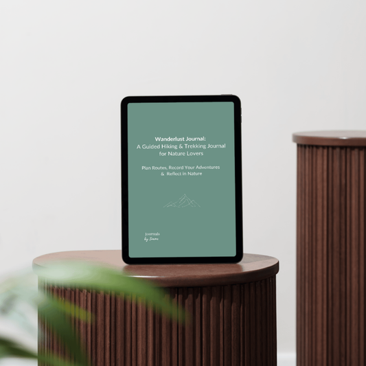 Tablet displaying the cover of the wanderlust journal on a wooden stand with a blurred plant in the foreground.