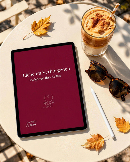 Liebe im Verborgenen als PDF auf dem Tablet, Bordeaux-Cover auf einem Bistrotisch mit Iced Pumpkin Latte, Pencil und Herbstlaub